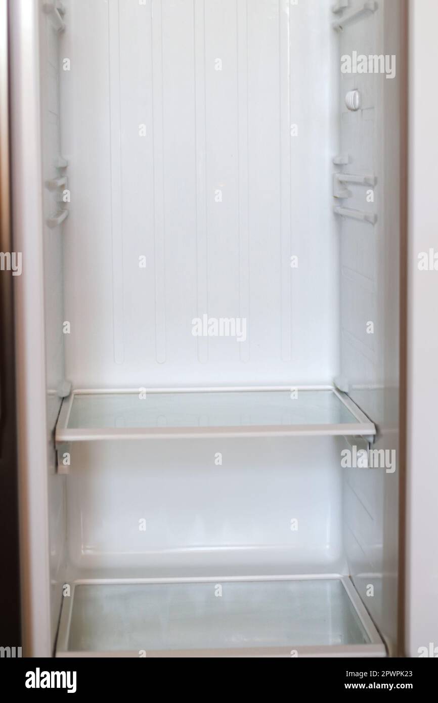 Empty open fridge with shelves, refrigerator. Inside of an empty white fridge. Vertical. Closeup. Out of focus Stock Photo