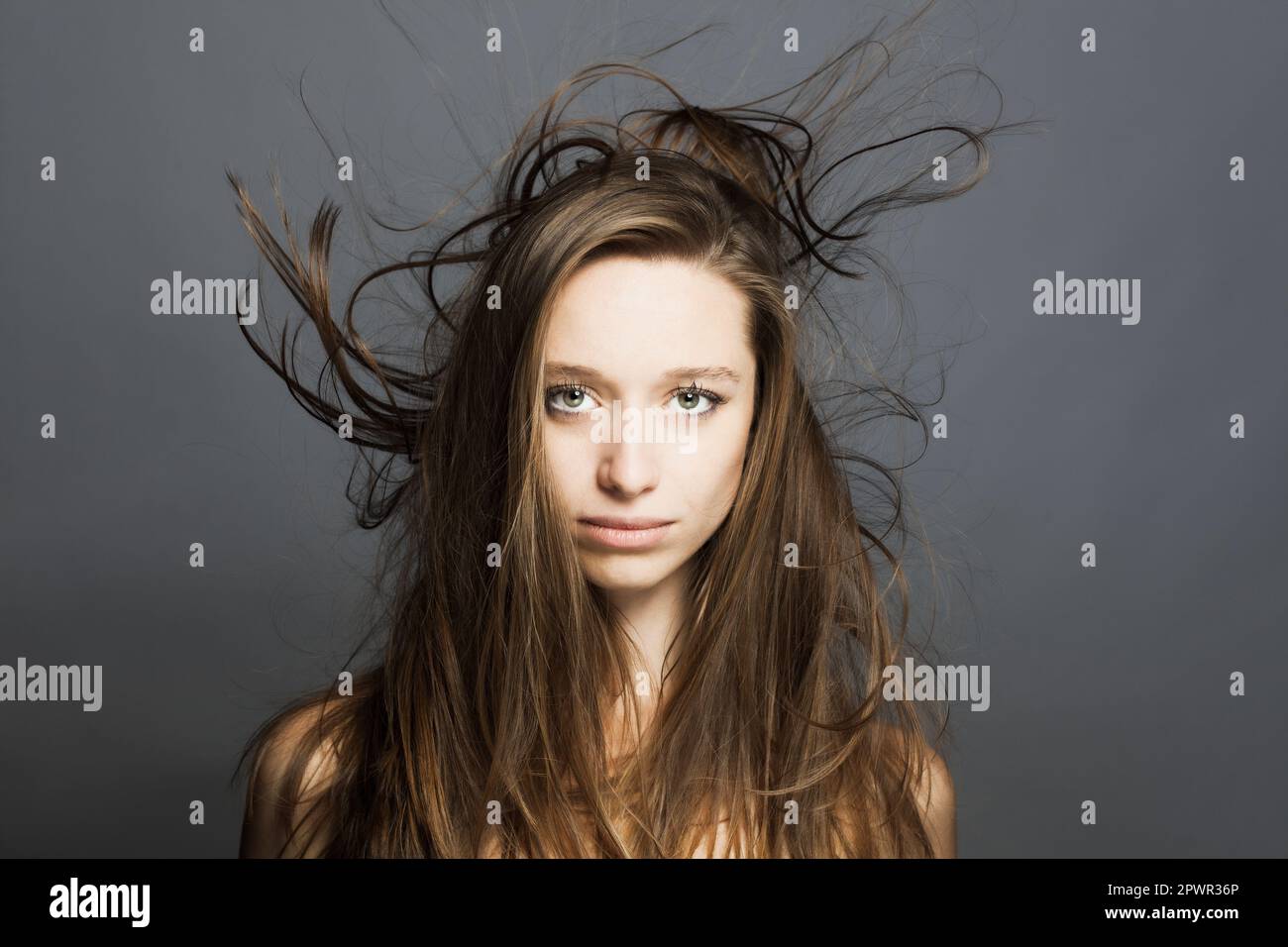 girl with flowing hair in the air studio portrait against gray