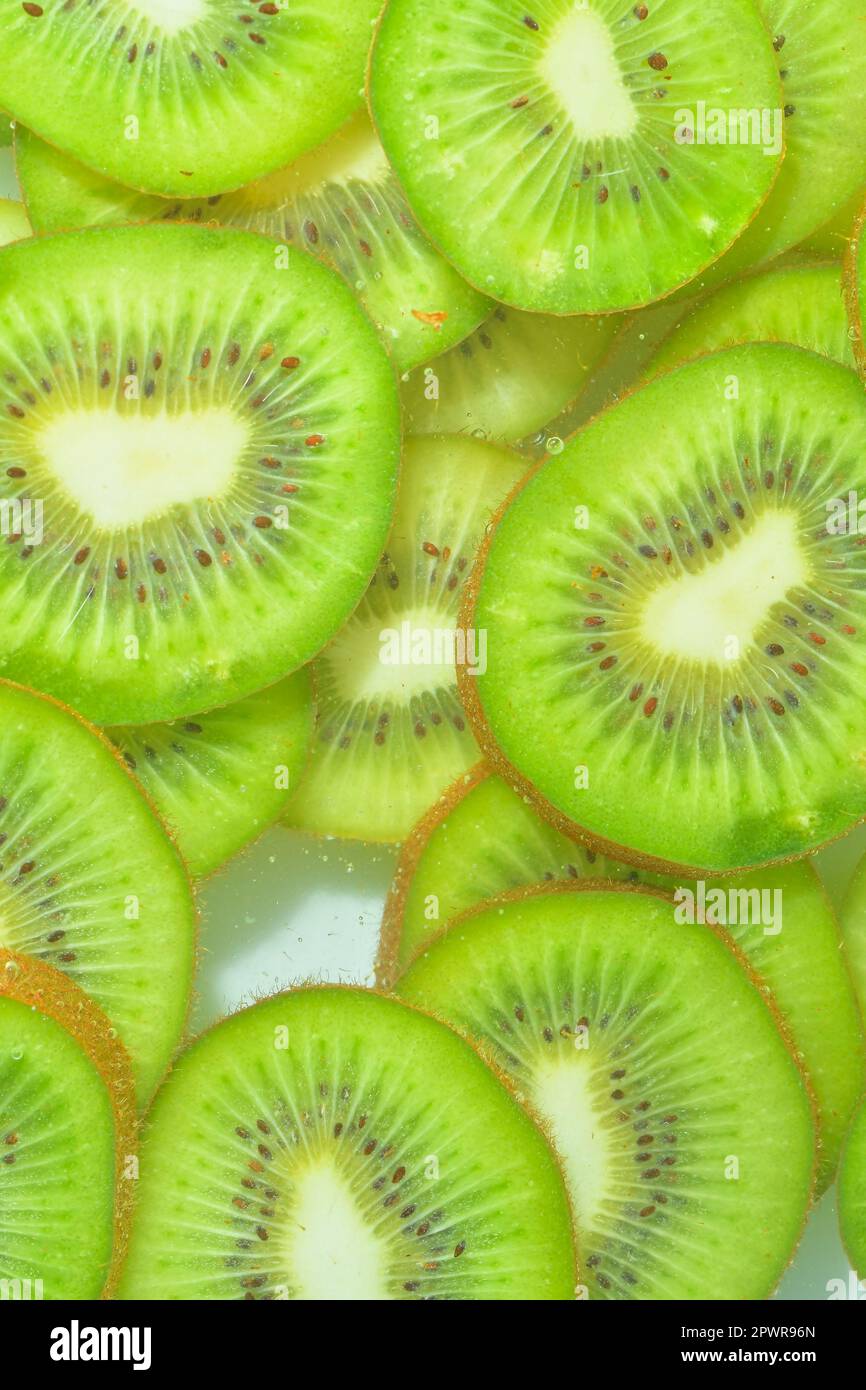Close-up view of the green kiwi fruit slices in water background ...