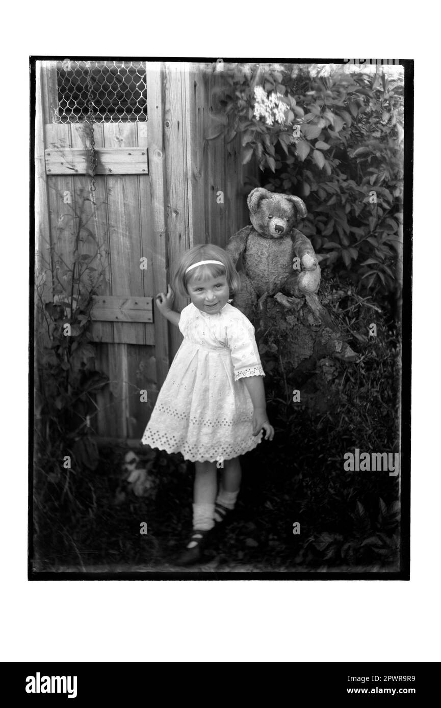 Young Girl and Teddy Bear in Garden Stock Photo