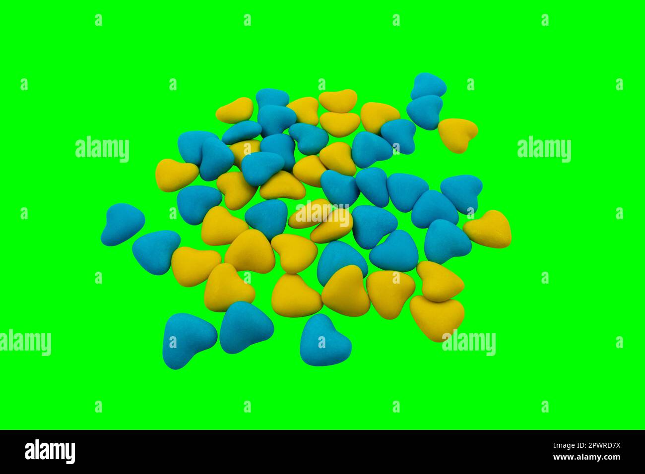 A bunch of yellow and blue heart-shaped candies (close-up) on a green background (chroma key). State symbols of Ukraine. View from above Stock Photo