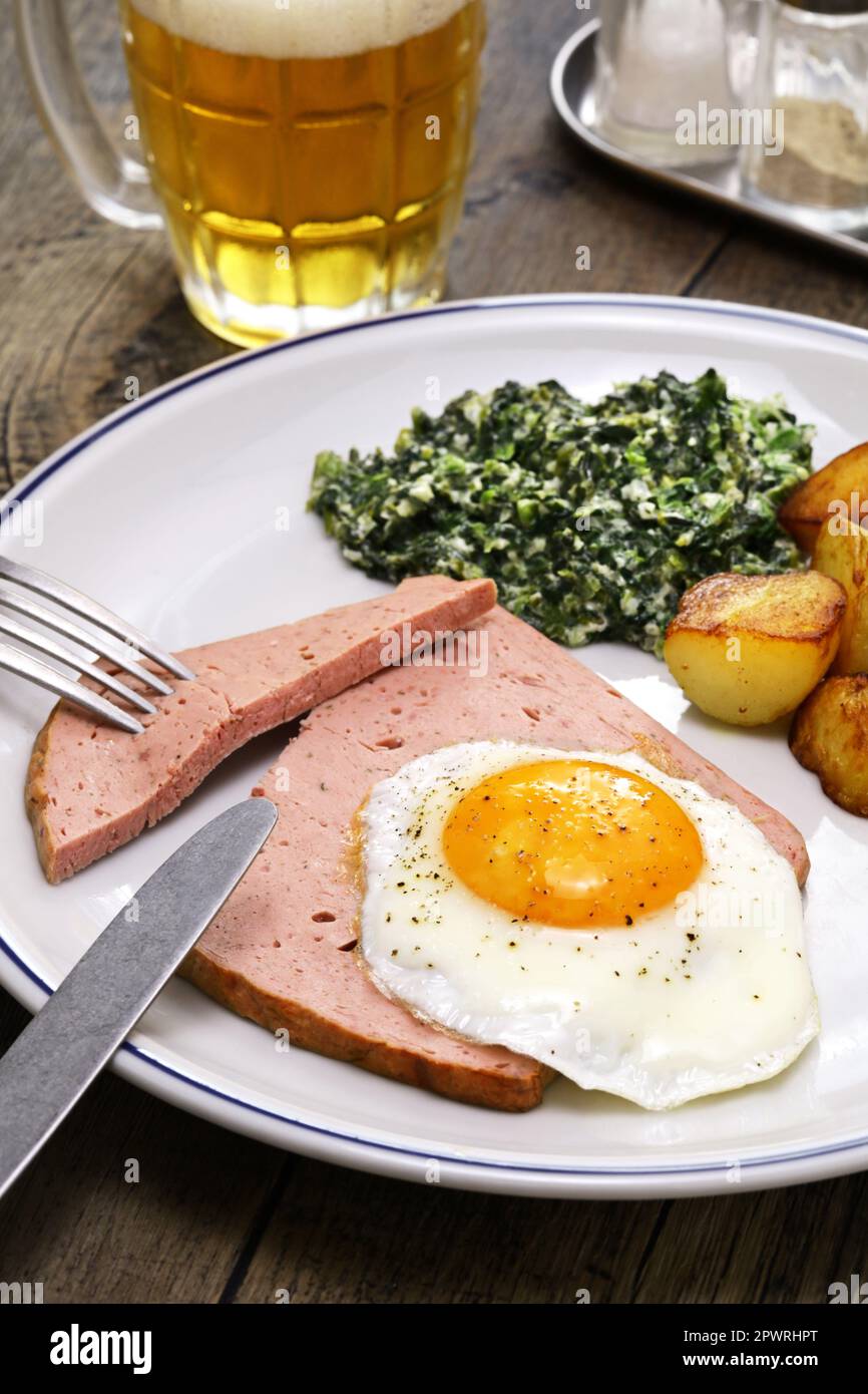 Leberkäse with spinach, potatoes and fried egg, Austria and southern German dish Stock Photo