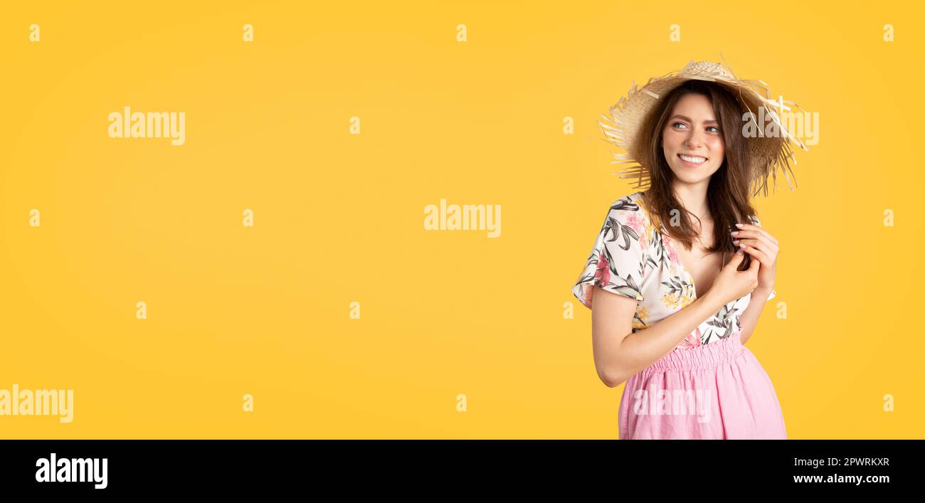 Lovely european woman in beautiful dress and straw hat posing on yellow ...