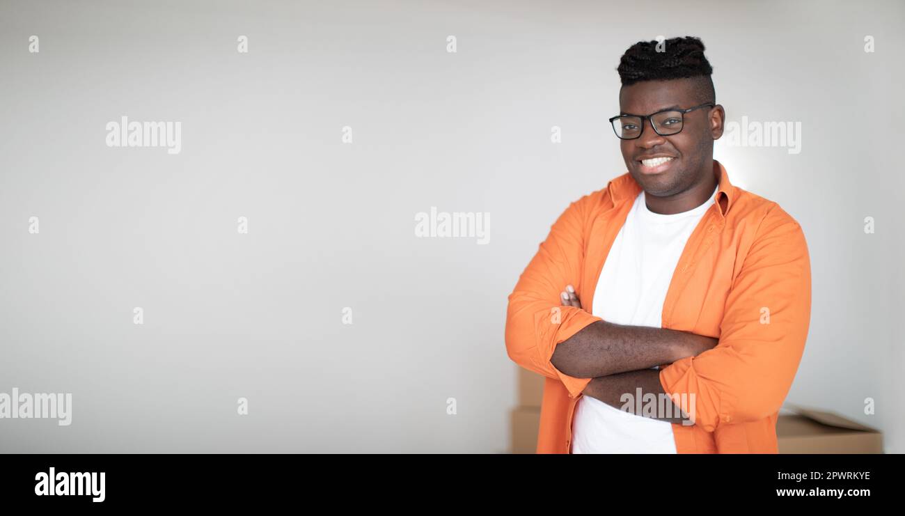 Handsome Black Guy Standing With Folded Arms And Looking At Camera Stock Photo