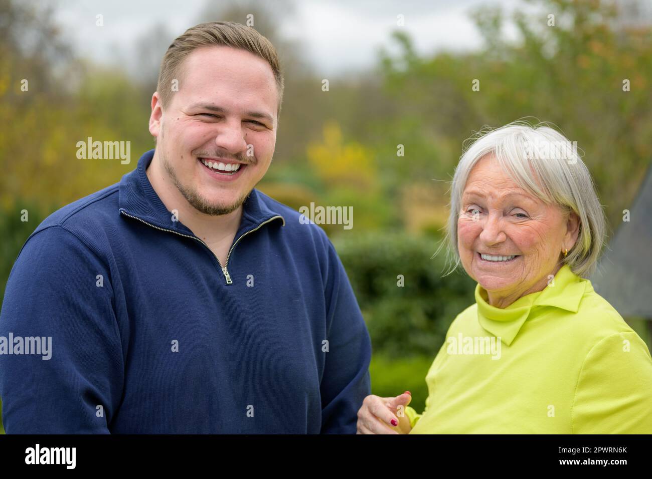 Two generation family, grandmother and grandson standing next to each other laughing Stock Photo