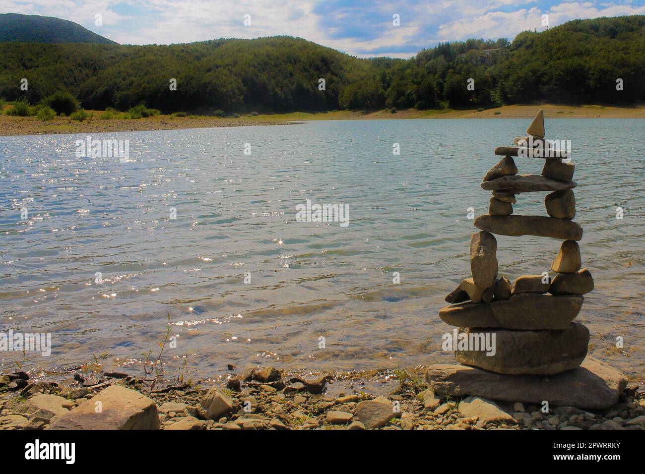 Pyramid of the stones on the beach against mountains and lake. Concept of spirituality, relax, zen. Stock Photo