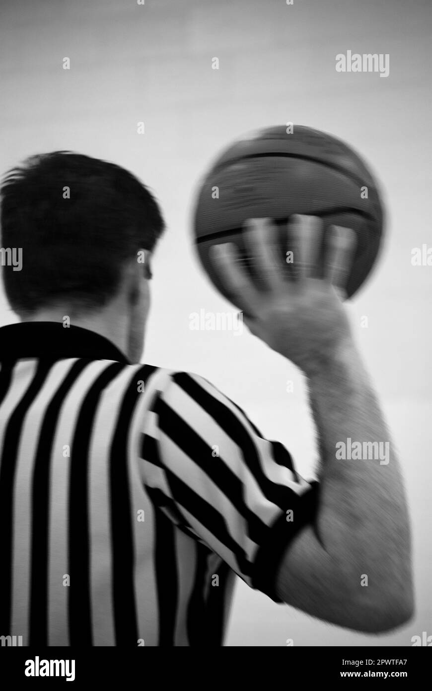 Basketball Referee holding ball black and white stripes on shirt calling game Stock Photo
