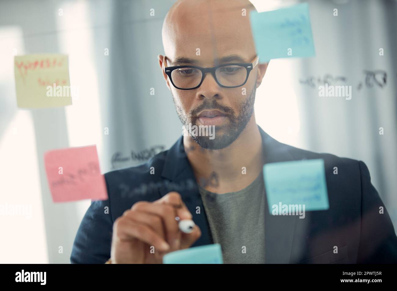 Im impressing myself with all these awesome ideas. a young businessman brainstorming with notes on a glass wall in an office Stock Photo
