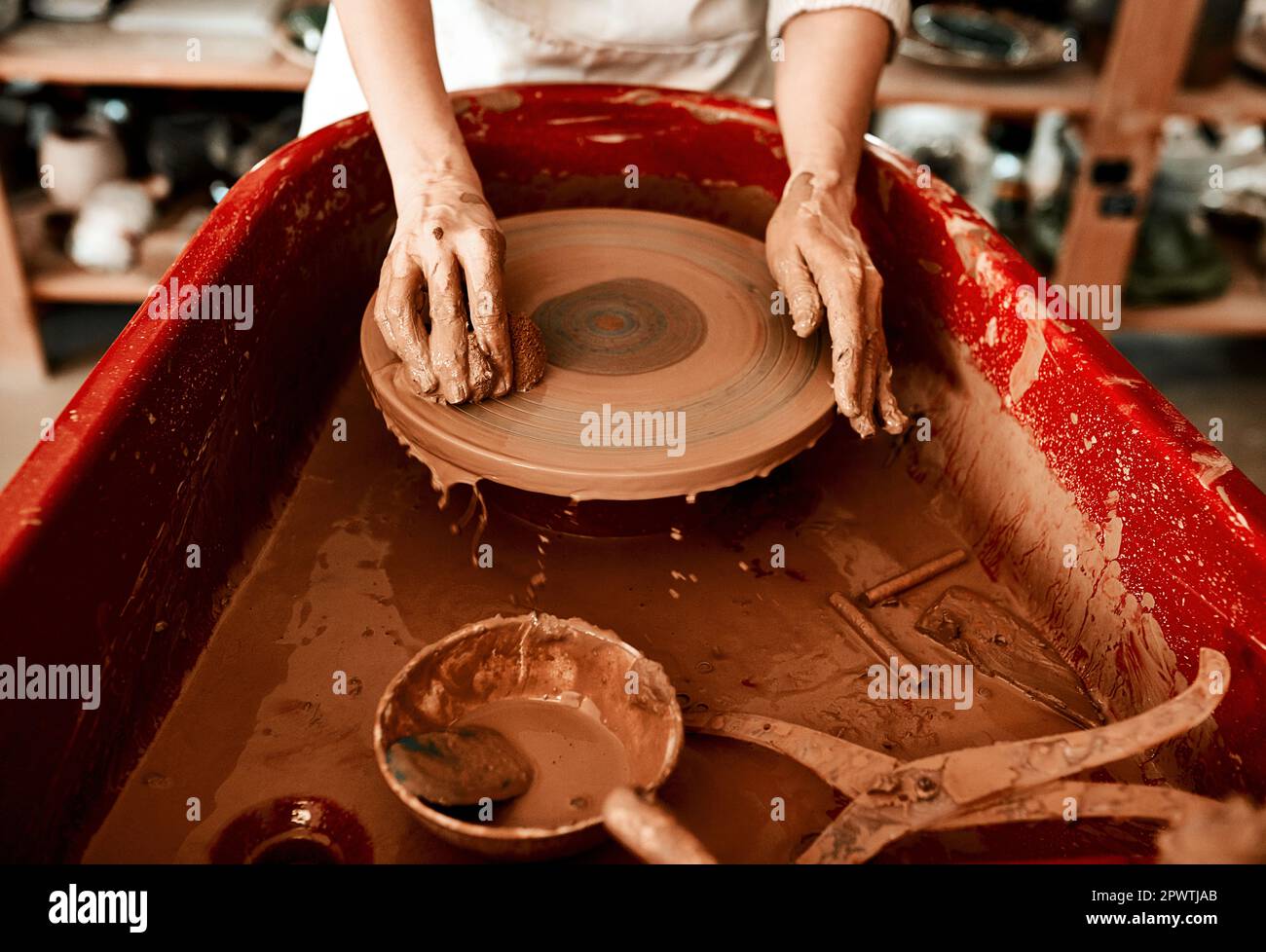 Pottery is a messy business. an unrecognizable woman molding clay on a