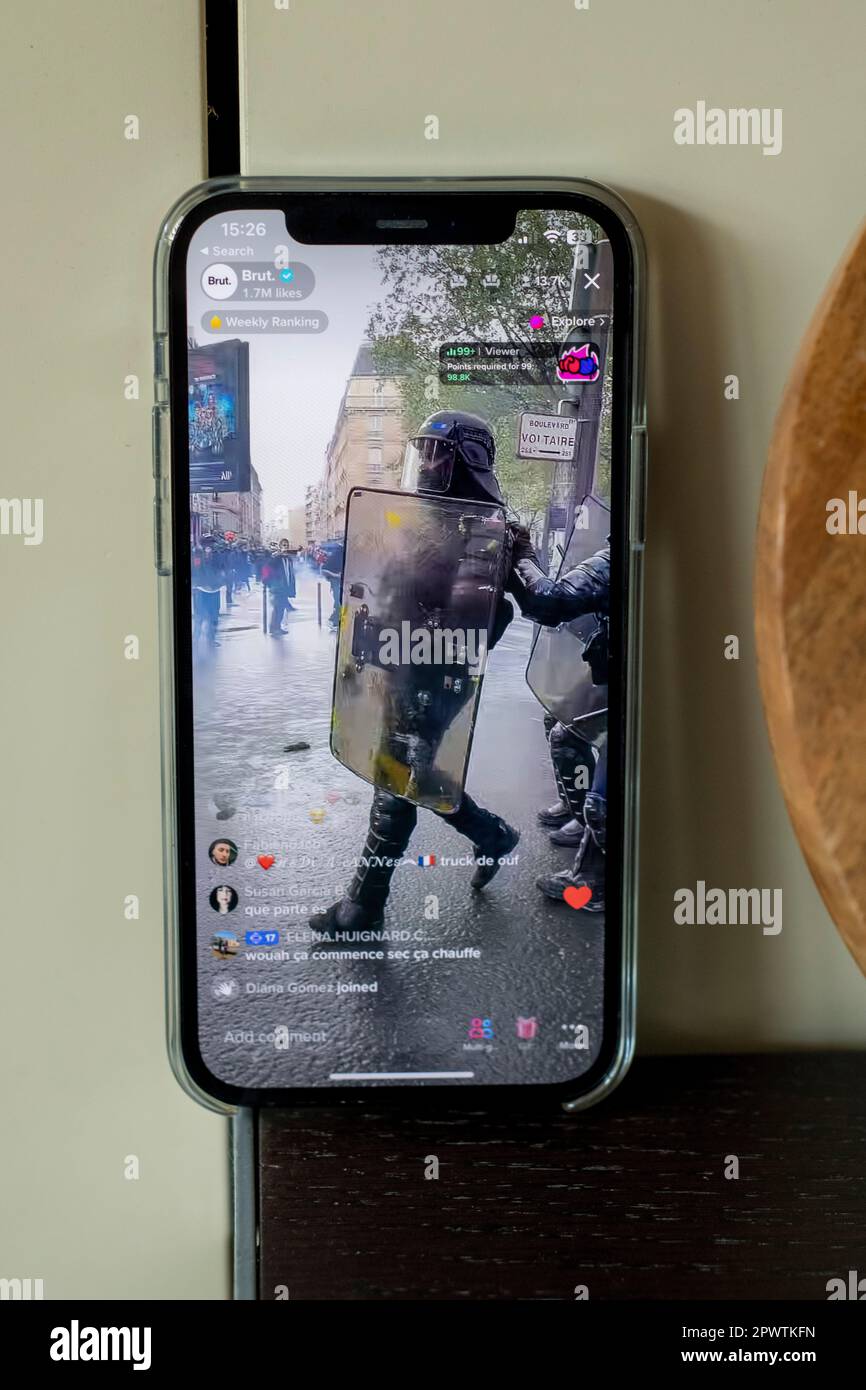 Pictures of an iphone12 live streaming the riots in Paris on the 1st of May 2023, here a police officer in riot gear with shield and helmet. Stock Photo