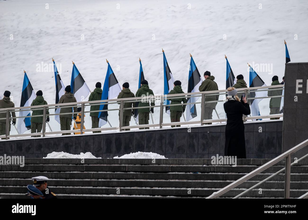 Young Estonians holding their flags on the top of the main square in Tallinn during the independence day celebration, accompanied by a military parade Stock Photo