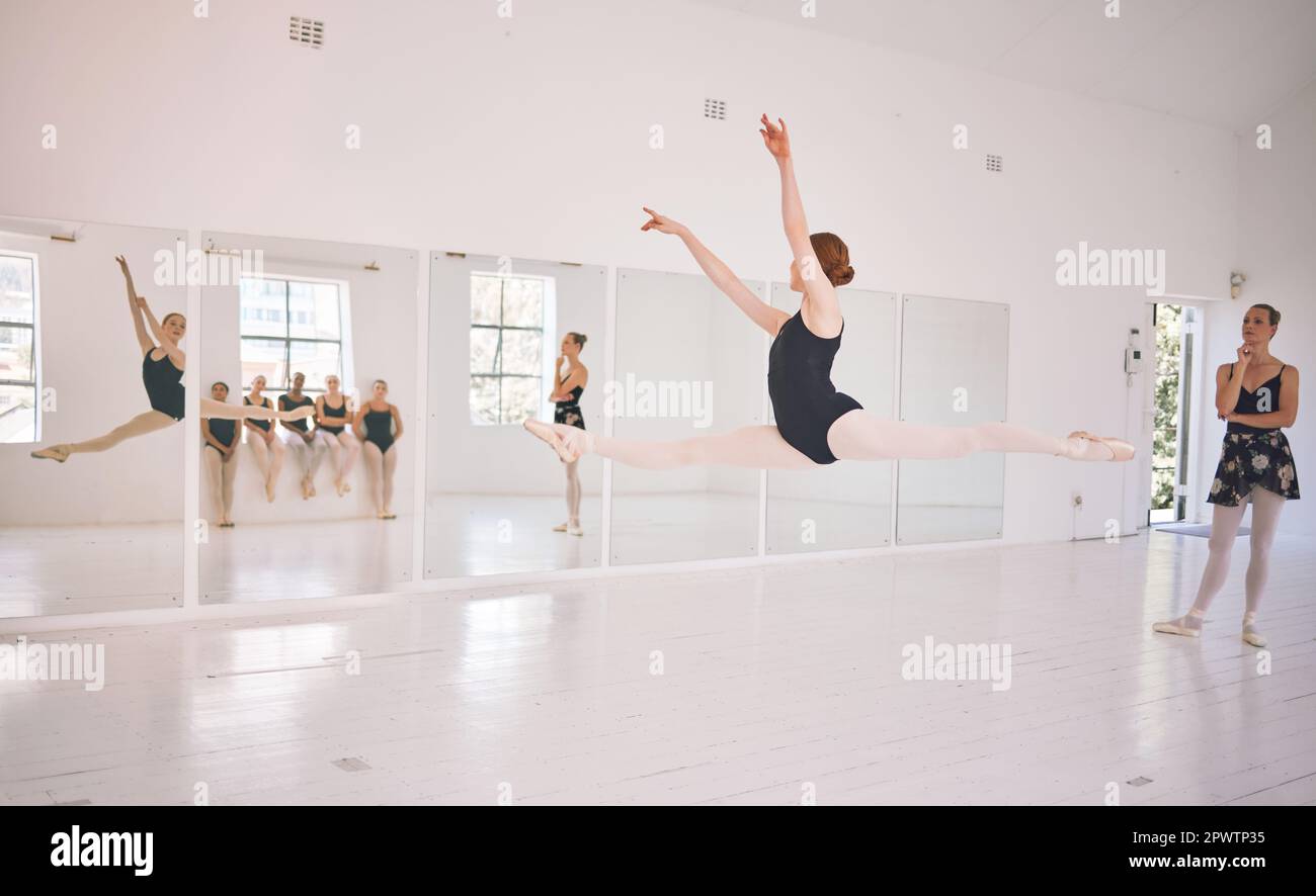 Young woman dance instructor teaching a ballet class to a group of a children in her studio. Ballerina teacher working with girl students, preparing f Stock Photo