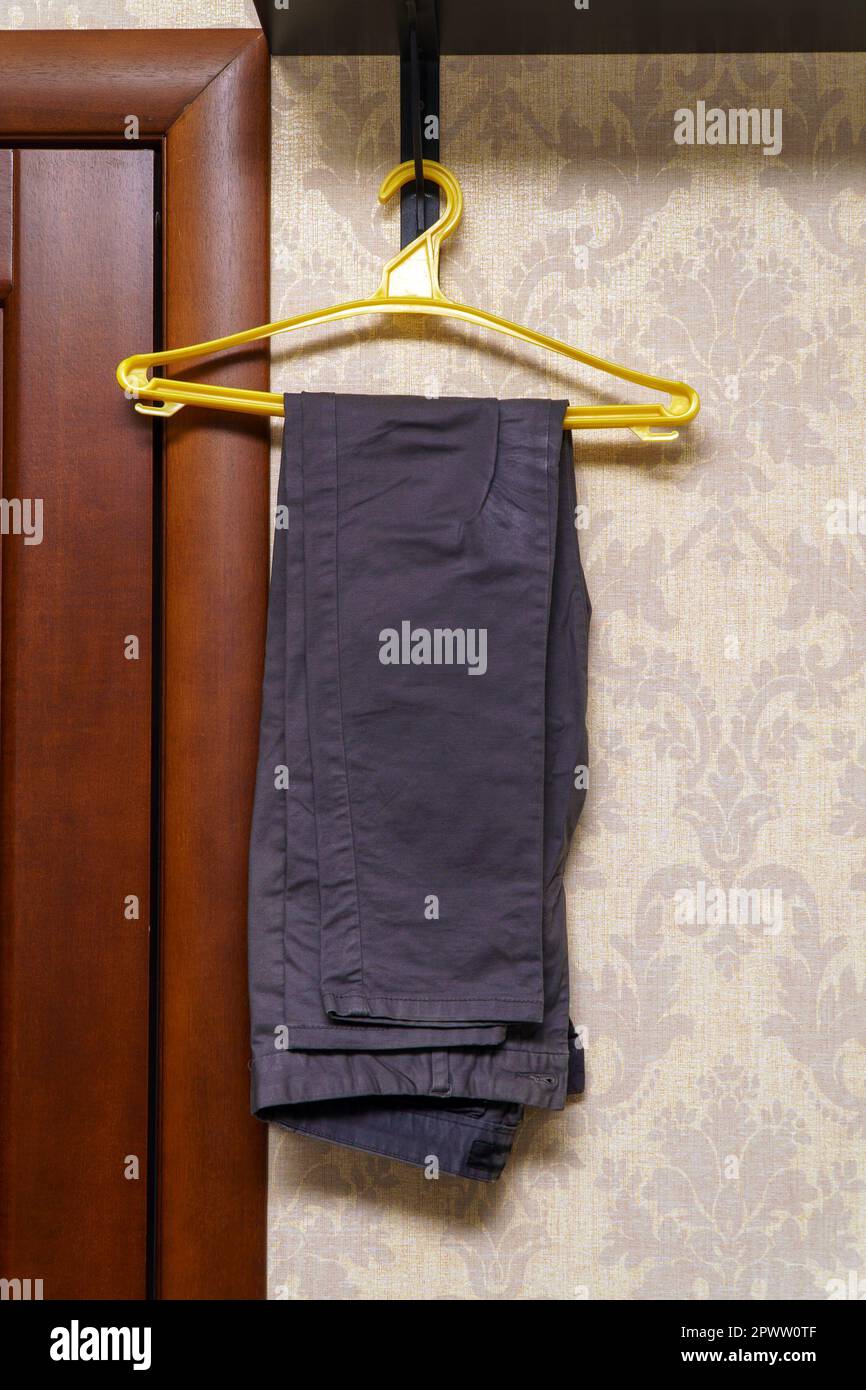 Folded gray trousers hang on a plastic hanger Stock Photo