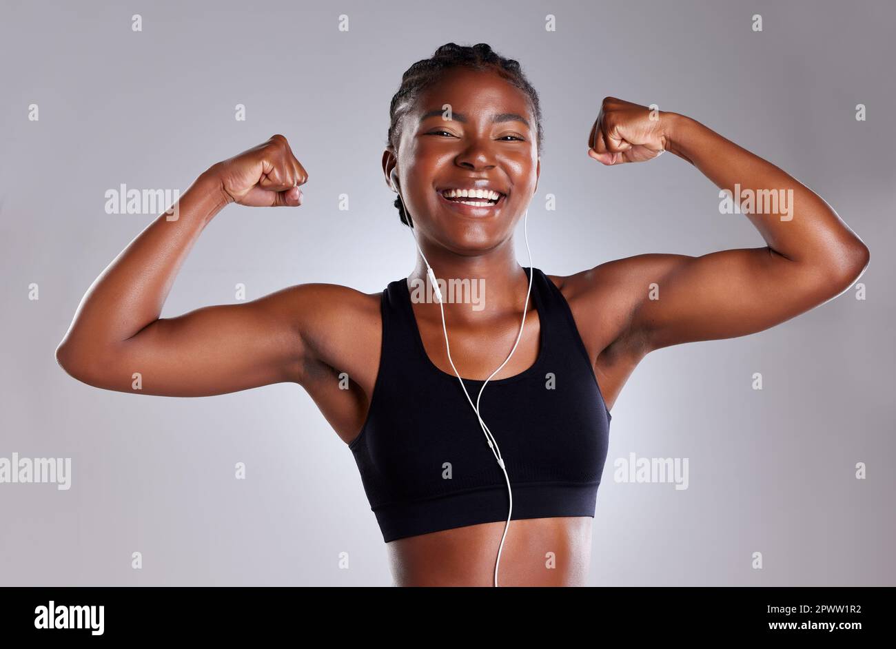 Happy Athletic Woman Flexing Her Bicep At Home High-Res Stock