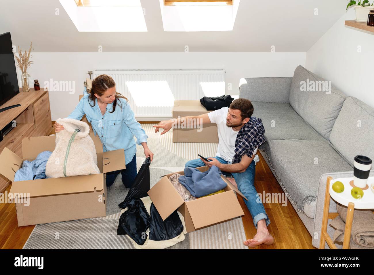 Young married couple packing their clothes for charitable organisation. Stock Photo
