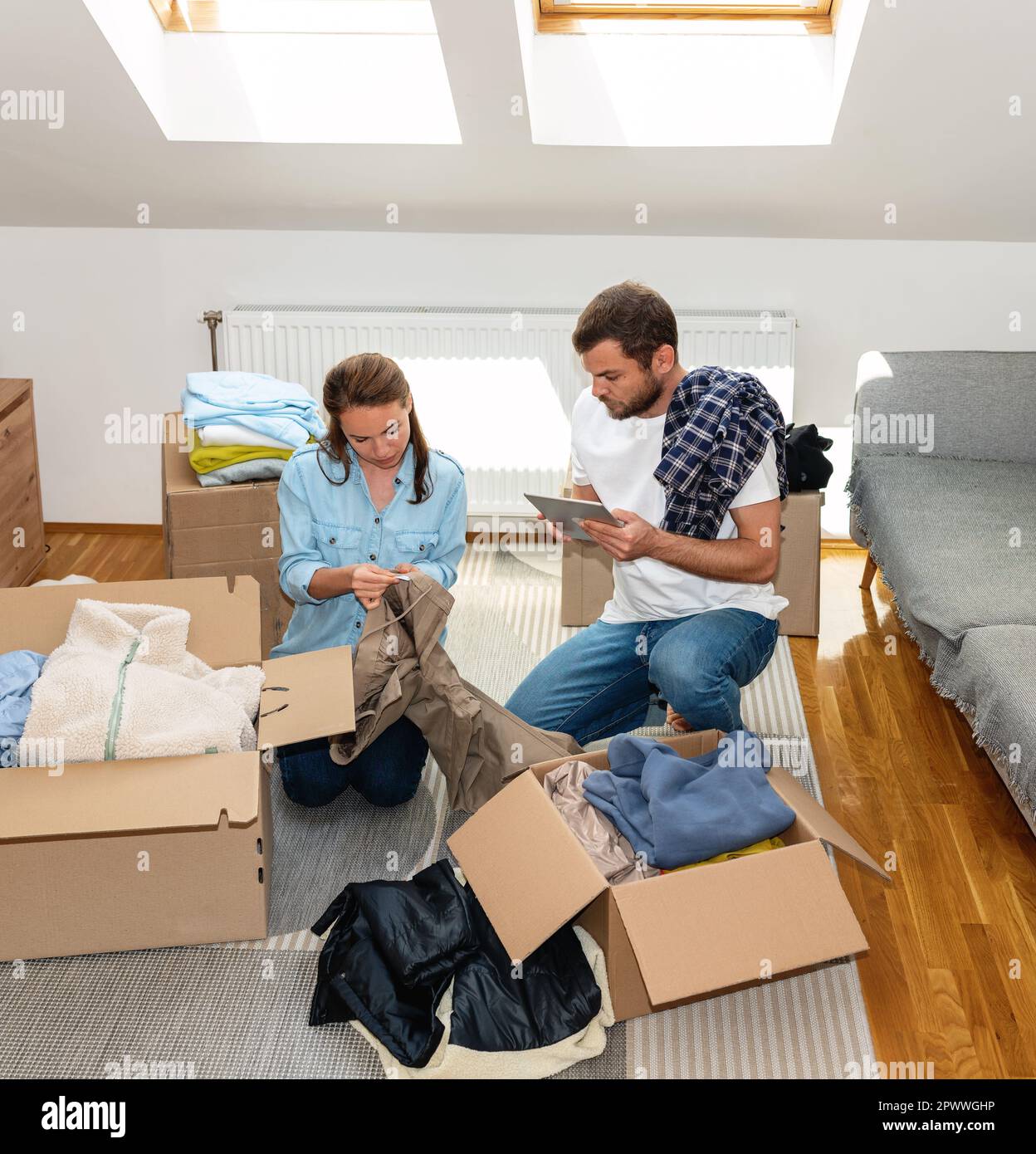 Volunteers woman and man inventory and packing clothes for donation. Stock Photo