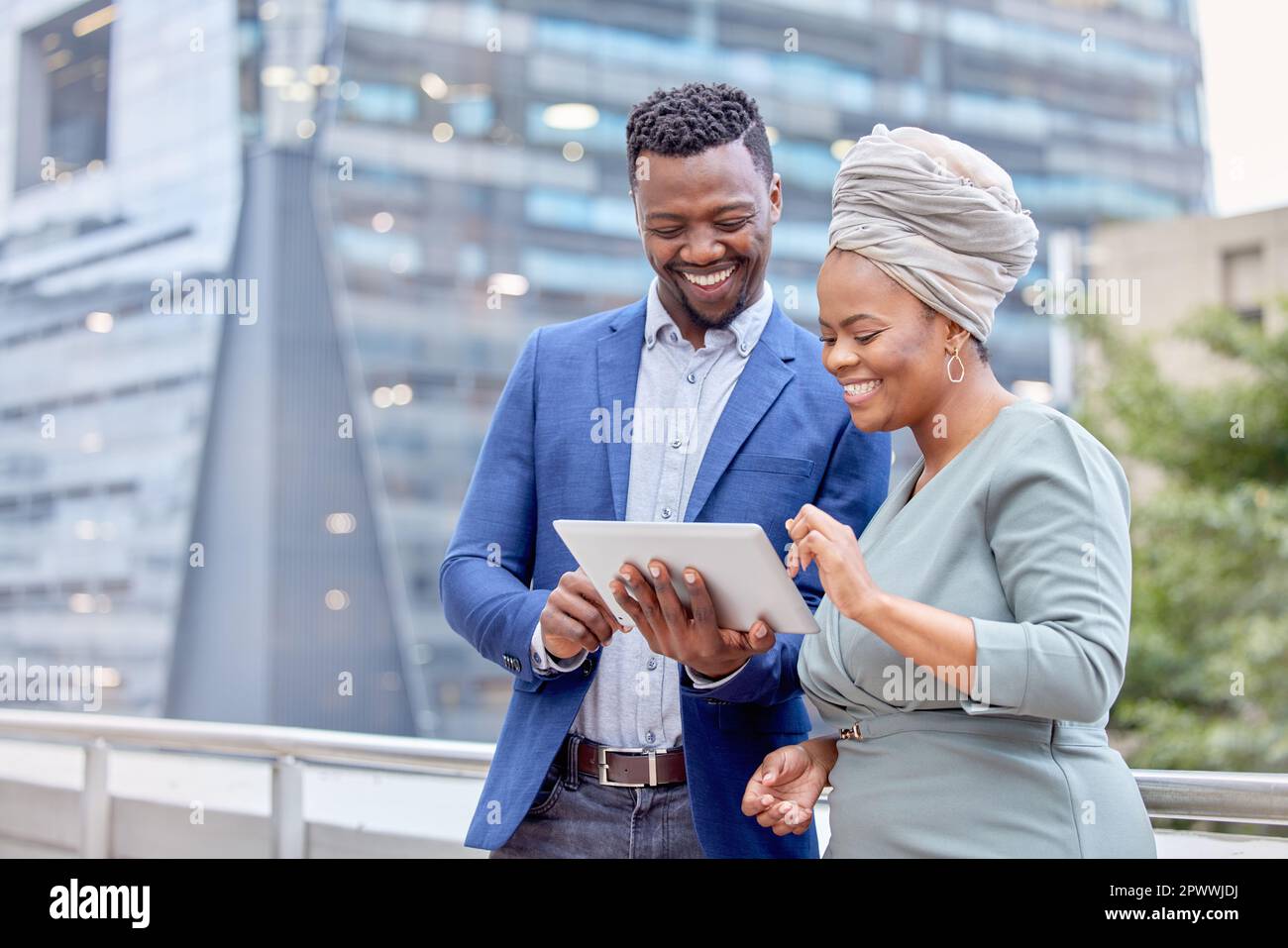 Technology brings us together. two colleagues using a digital tablet together against a city background Stock Photo