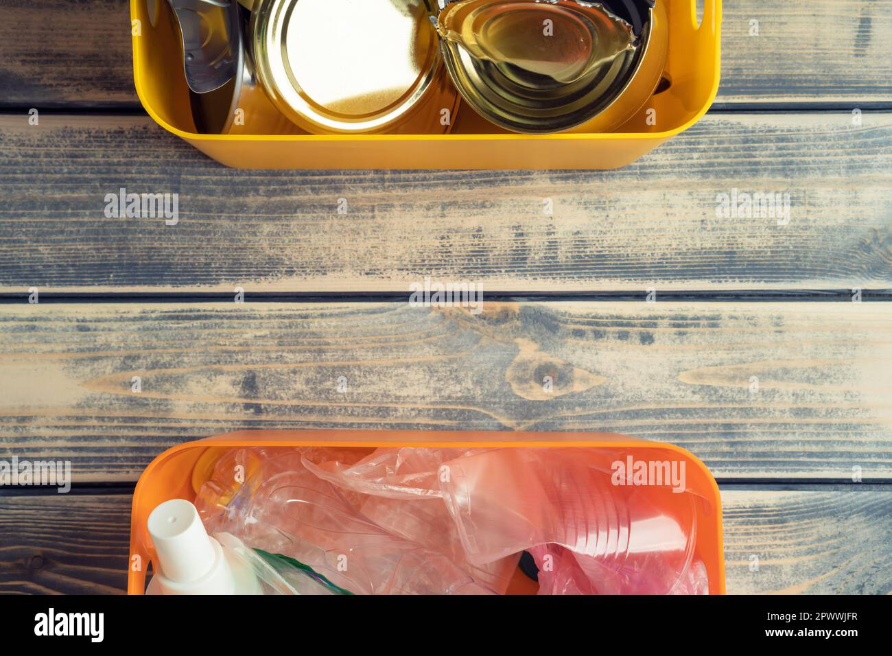 Two halves of containers with metal canned goods and plastic waste on