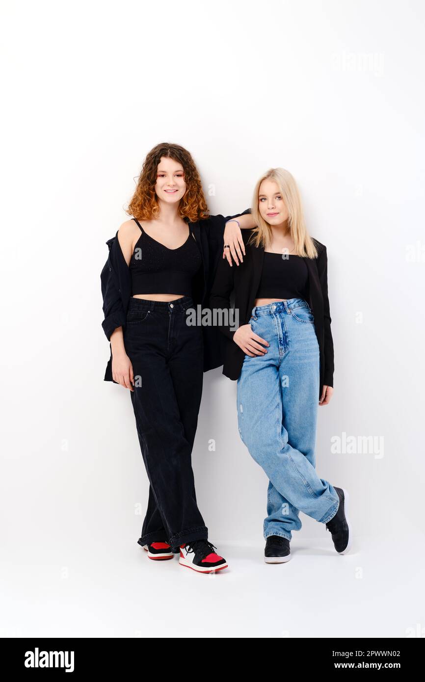 Two teen girls lean on each other over white studio background Stock Photo