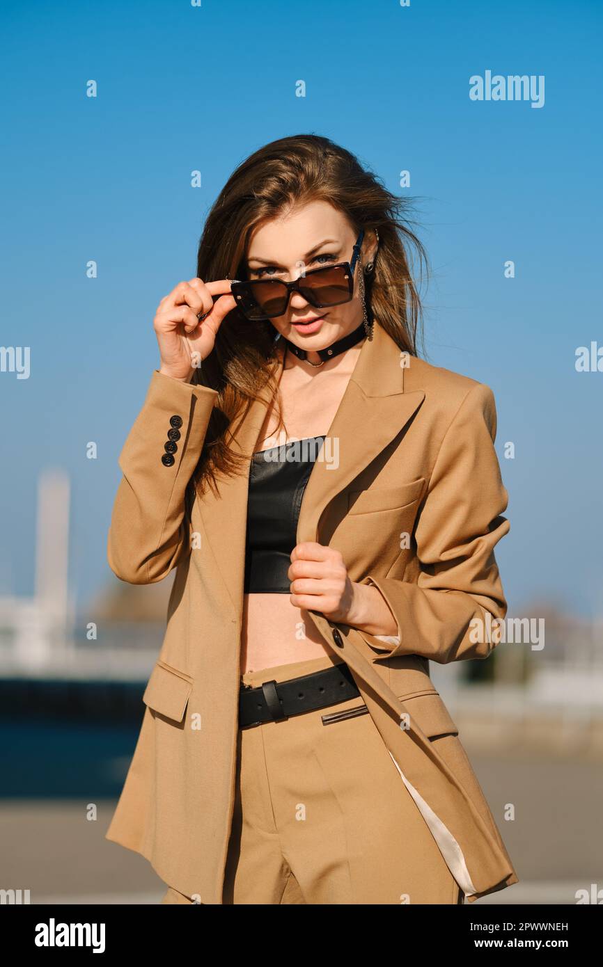 Street fashion, women casual and trendy outfit. Woman in pantsuit, leather tank-top and rough boots outdoor. Stock Photo