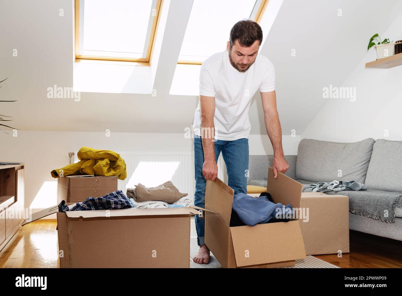 Man packing his old apparel into cardboard boxes at home, reusing, second hands concept. Stock Photo