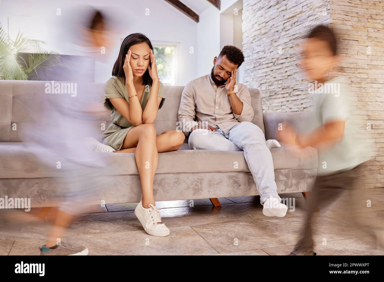 Sofa, family and tired with fast children running with speed in living room of house together. Fatigue, exhausted or headache of young parents at home Stock Photo