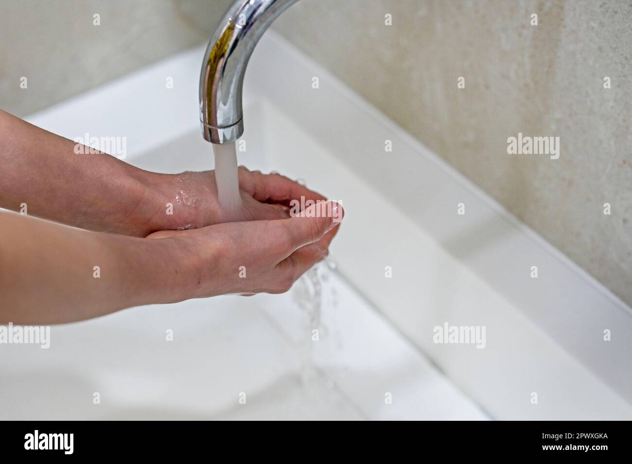 child thoroughly washes his hands under the pressure of water from