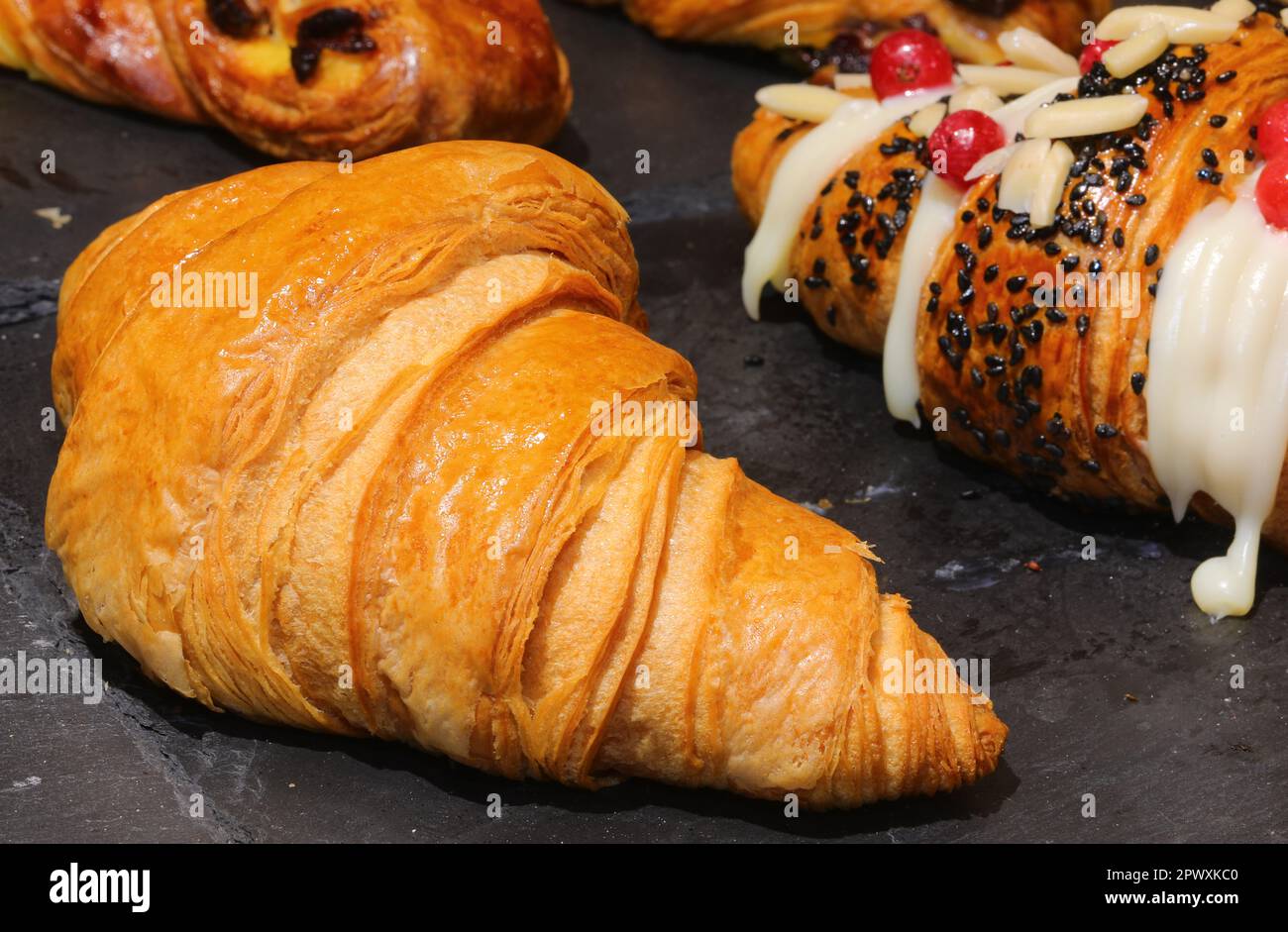 Baked brioche garnished with sweet icing and fresh fruit for sale in the bakery Stock Photo