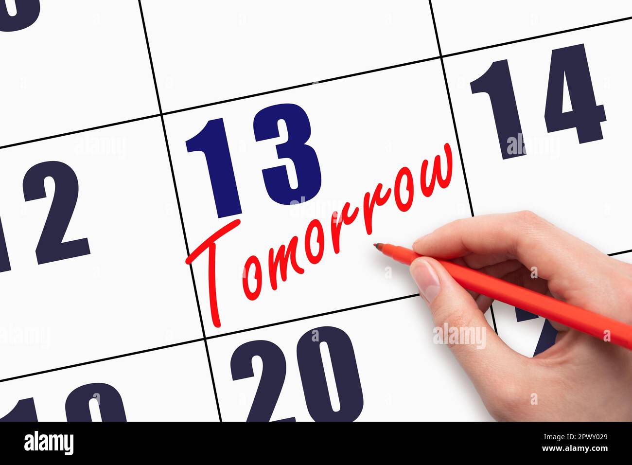13th day of the month. Hand writing text TOMORROW on calendar date ...