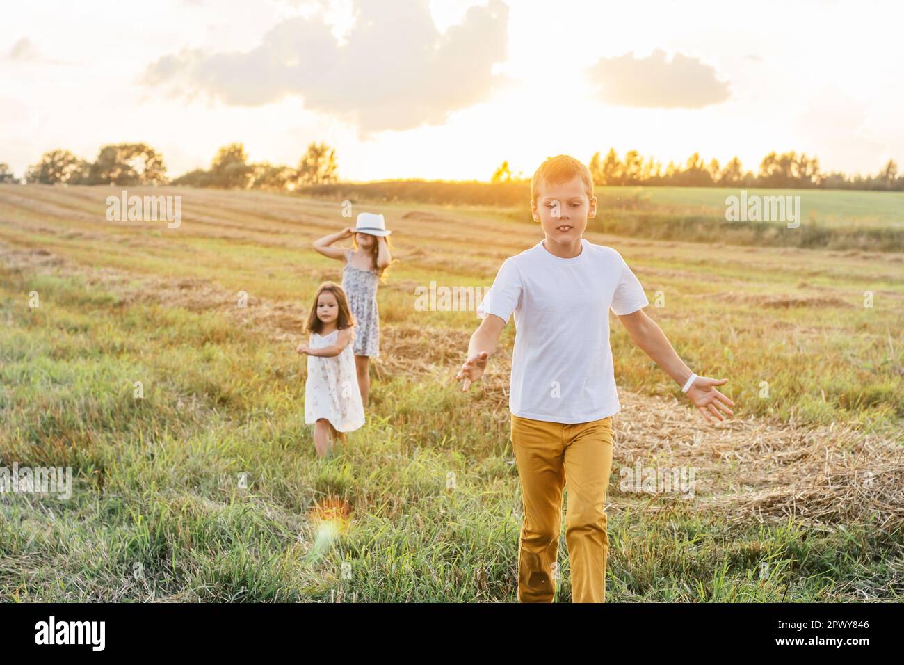 Portrait of three children playing game of catch, jumping and running