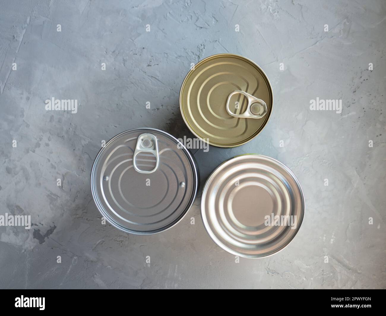 Various canned foods in tin cans on concrete grey background. Non-perishable, long shelf life food for survival in emergency conditions. Food supplies Stock Photo