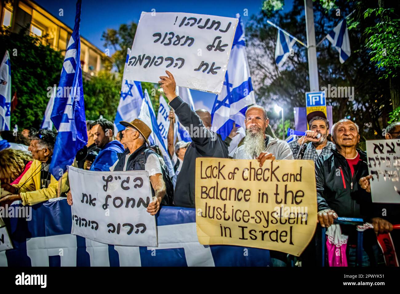 Tel Aviv, Israel. 30th Apr, 2023. Protestors wave the Israeli flag and hold placards as they demonstrate against former chief Justice Aharon Barak in Tel Aviv. Hundreds of pro and anti-judicial reform protesters gathered outside the home of former High Court Justice president Aharon Barak on Sunday, after anti-reform groups expressed concern for his safety earlier in the day. Credit: SOPA Images Limited/Alamy Live News Stock Photo