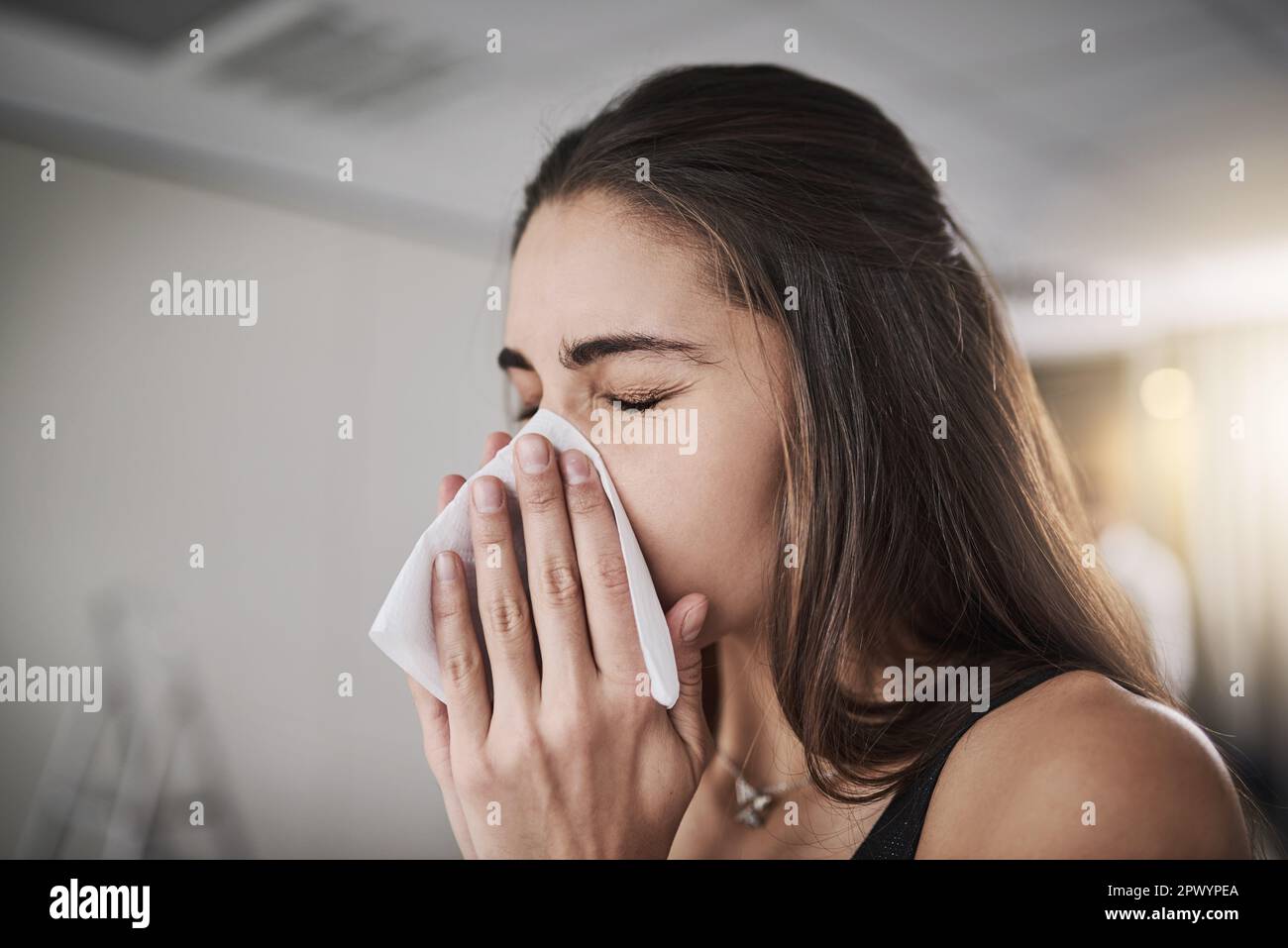 Flu seasons coming knocking. a young woman blowing her nose Stock Photo
