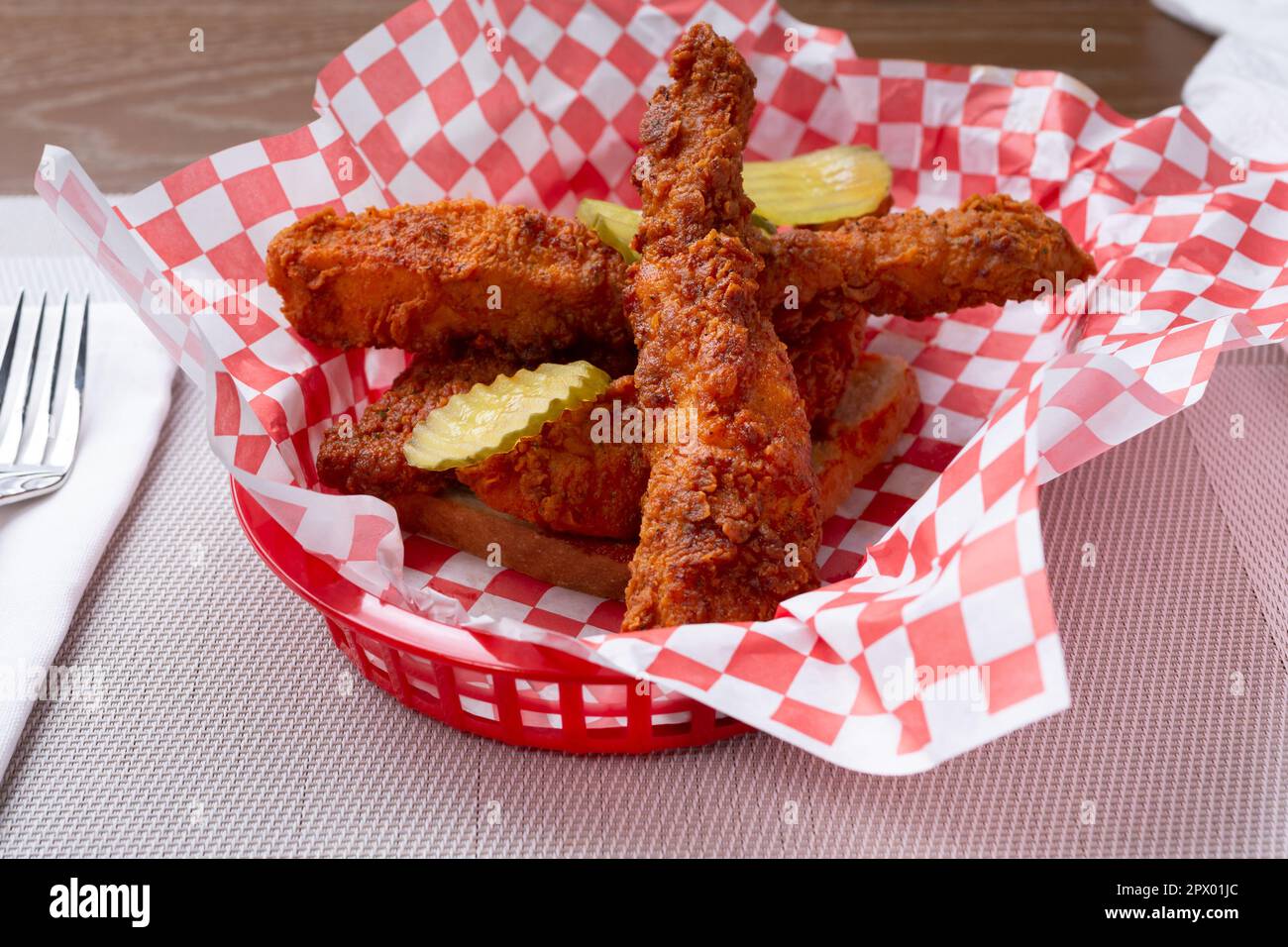 A view of a basket of spicy breaded chicken strips over a slice of ...