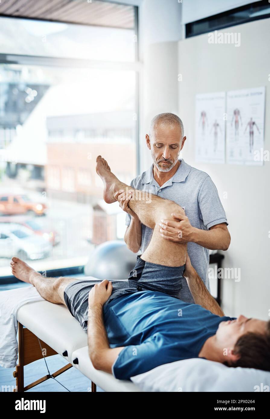 With careful exercises, your pain will soon be relieved. a physiotherapist treating a patient Stock Photo