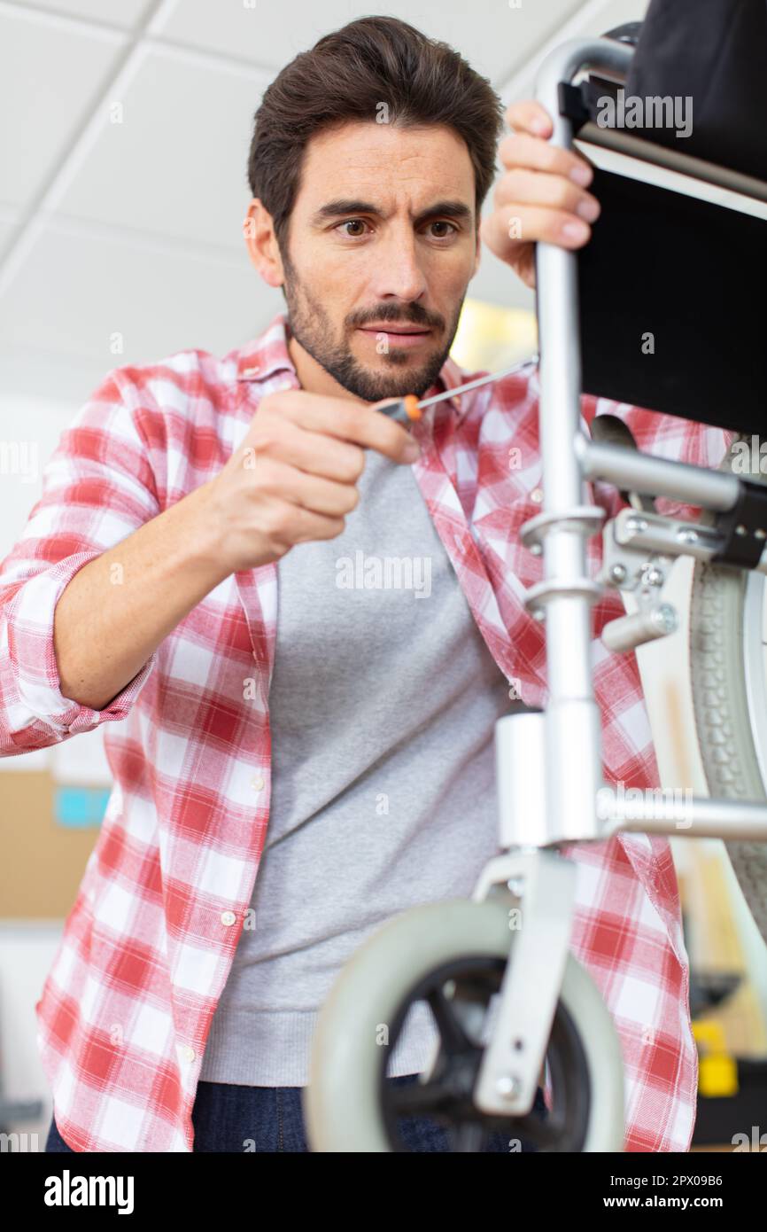 young man repairing a broken wheelchair part Stock Photo Alamy