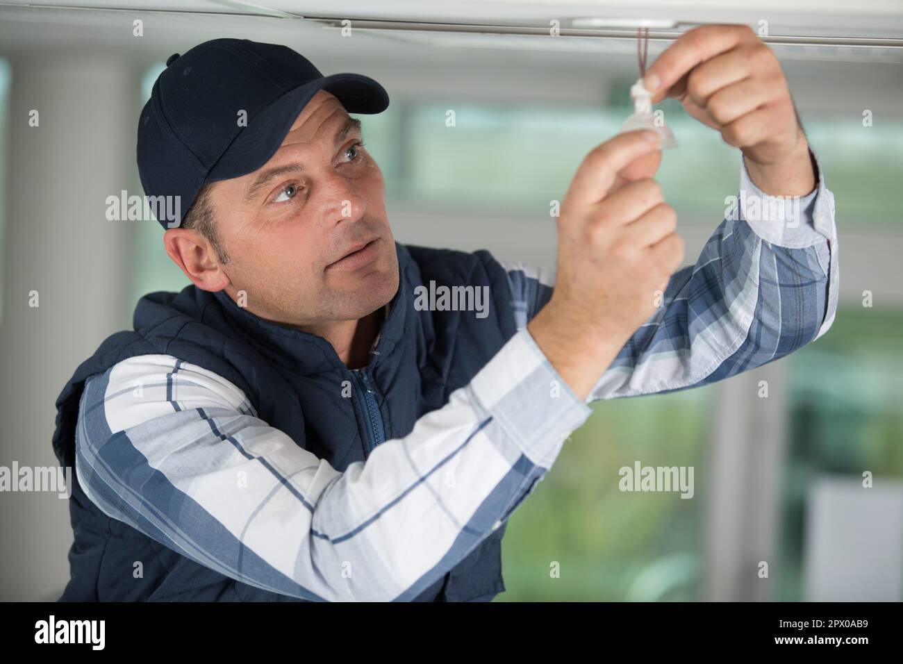 male electrician mounting light on ceiling Stock Photo - Alamy