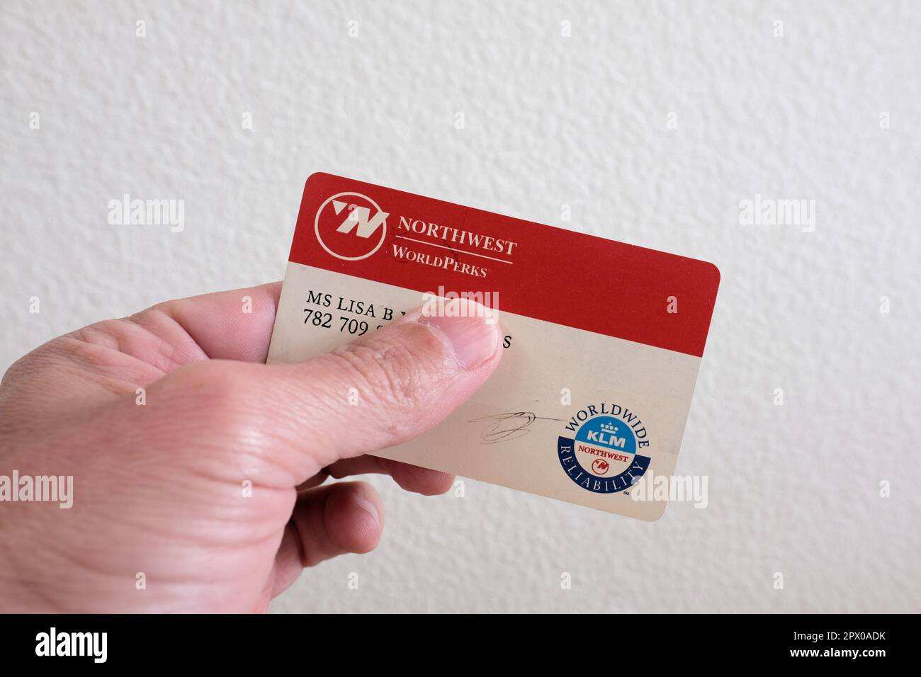 Hand holding a Northwest Airlines WorldPerks frequent flyer program card, travel partner with