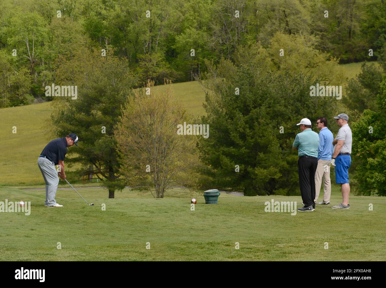 A golf pro gives tips to three students at a country club golf course A golf pro gives tips to three students at a country club golf course