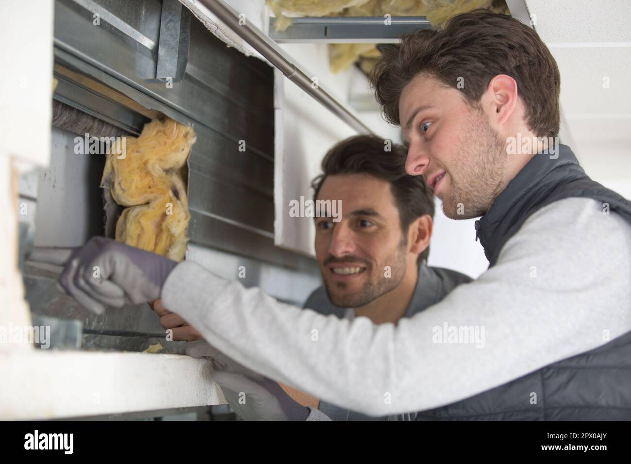 two men working with foiled insulation on the window sill Stock Photo
