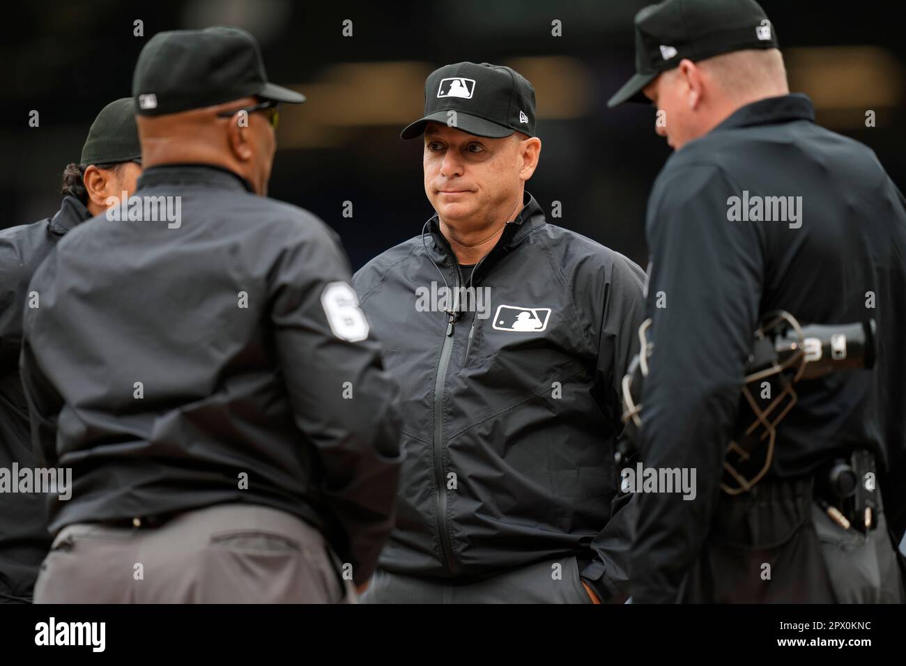 Umpire Andy Fletcher, center, meets with umpires Erich Bacchus, from