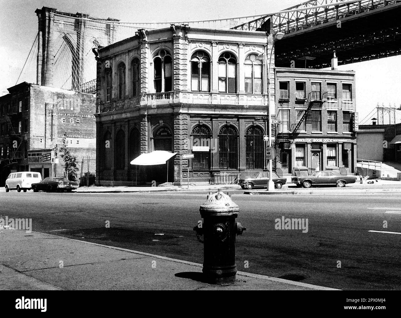 AJAXNETPHOTO. JULY, 1975. BROOKLYN, NEW YORK, USA. - OLD BANK - BROOKLYN BRIDGE TOWER EMERGING BEHIND NINETEENTH CENTURY COMMERCIAL BUILDINGS ON THE CORNER OF FRONT STREET AND CADMAN PLAZA WEST; THE OLD FULTON FERRY BANK AND TO ITS LEFT, THE OLDEST REMAINING 19TH CENTURY COMMERCIAL BUILDING BELOW THE DECK OF THE BROOKLYN BRIDGE SPANNING EAST RIVER BETWEEN PARK ROW MANHATTAN AND SANDS STREET, BROOKLYN, NEW YORK CiTY.  PHOTO:JONATHAN EASTLAND/AJAXREF:232404 120 Stock Photo