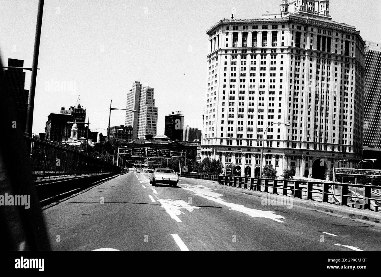 AJAXNETPHOTO. JULY, 1975. NEW YORK, USA. - LOWER MANHATTAN SKYLINE - SEEN FROM BROOKLYN BRIDGE EXIT RAMP HEADING IN TO CITY. ON RIGHT IS THE 40 STORY DAVID N DINKINS MUNICIPAL BUILDING DESIGNED BY MCKIM, MEAD AND WHITE.  PHOTO:JONATHAN EASTLAND/AJAXREF:232404 103 Stock Photo