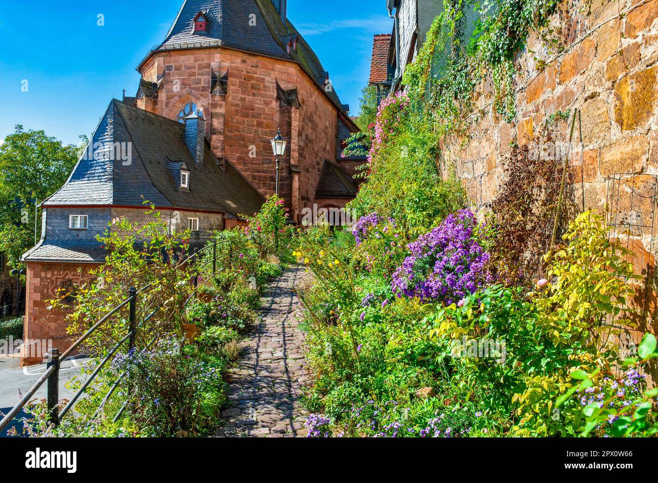 The 'Kugelkirche' in the historic old town of Marburg an der Lahn with a flower-framed footpath Stock Photo