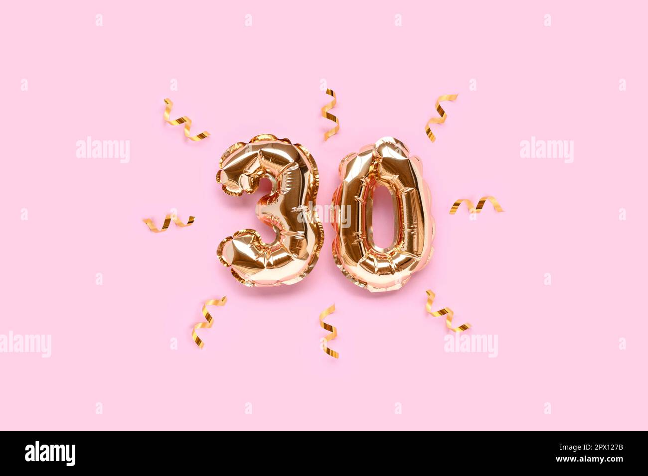 Number 30 gold air balloons with ribbon confetti on a pink background. Stock Photo