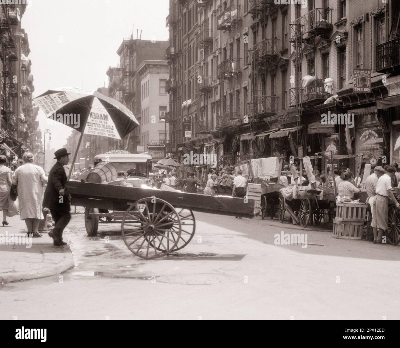 1930s PUSH CART VENDORS SELLING EVERYTHING FOOD FRUITS AND VEGETABLES CLOTHES FABRIC SHOES LOWER EAST SIDE NEW YORK CITY NY USA - m3464 HAR001 HARS PERSONS SCENIC SHOPS UNITED STATES OF AMERICA MALES BUILDINGS NY TRANSPORTATION B&W NORTH AMERICA SHOPPER NORTH AMERICAN IMMIGRANTS SHOPPERS SELLING NEIGHBORHOOD ADVENTURE PROPERTY CUSTOMER SERVICE AND NETWORKING EXCITEMENT EXTERIOR VENDORS LES OPPORTUNITY NYC OCCUPATIONS STORES REAL ESTATE SIDEWALKS NEW YORK STRUCTURES CITIES EDIFICE NEW YORK CITY PUSH CART TENEMENT FIRE ESCAPES TENEMENTS COMMERCE EVERYTHING FRUITS PUSHCART BLACK AND WHITE Stock Photo