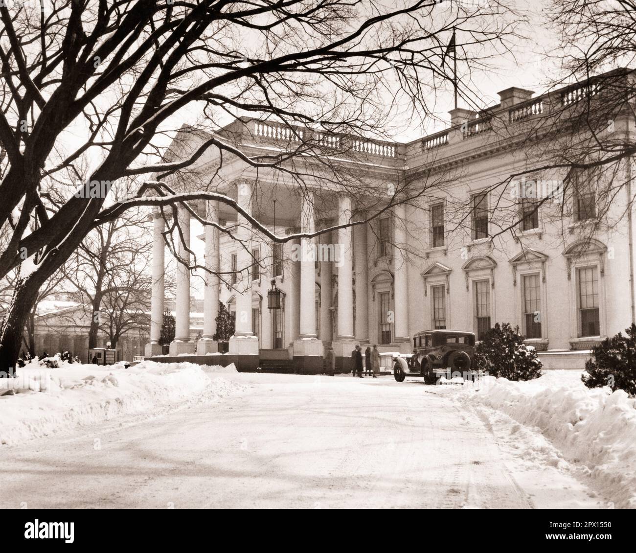1930s NORTH FACING FACADE OF THE WHITE HOUSE SURROUNDED BY WINTER SNOW WASHINGTON DC USA - q75049 CPC001 HARS THE WHITE HOUSE WINTERY CONCEPTS FACADE BLACK AND WHITE DISTRICT FEDERAL OLD FASHIONED PORTICO REPRESENTATION WHITE HOUSE Stock Photo
