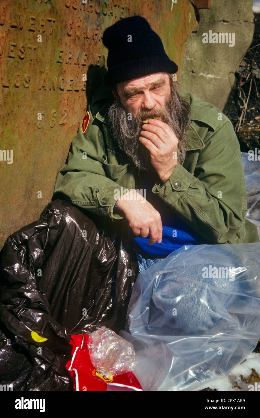 1990s BEARDED HOMELESS MAN VETERAN COVERED WITH PILES OF PLASTIC BAGS EATING A COOKIE  - kw12622 TRA001 HARS NERVOUS PILES TROUBLED HAZARD MIDDLE-AGED CONCERNED SADNESS MIDDLE-AGED MAN ANXIETY COVERED DANGEROUS HOMELESS WELFARE DESPAIR RISKY HAZARDOUS MOOD MENTAL HEALTH PERIL UNSAFE CONCEPTUAL GLUM BEARDED VETERAN DISADVANTAGED VET JEOPARDY TENSION DISAFFECTED DISAPPOINTED DISCONNECTED IMPOVERISHED MISERABLE CAUCASIAN ETHNICITY DISTRAUGHT MENTAL ILLNESS OLD FASHIONED Stock Photo