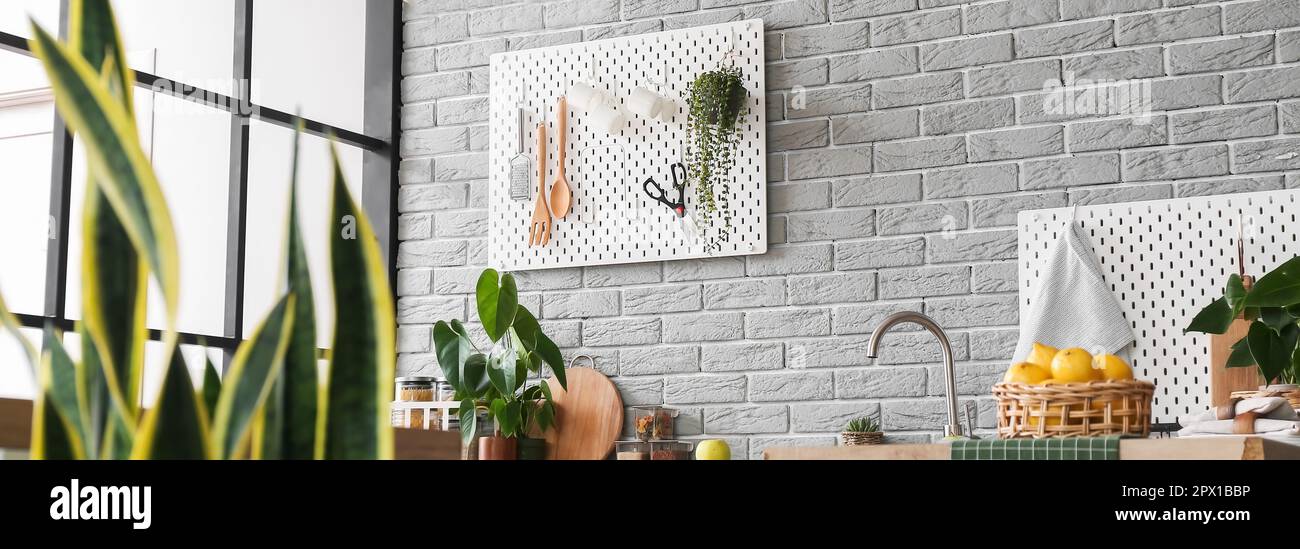 Kitchen interior with modern pegboards hanging on grey brick wall Stock Photo