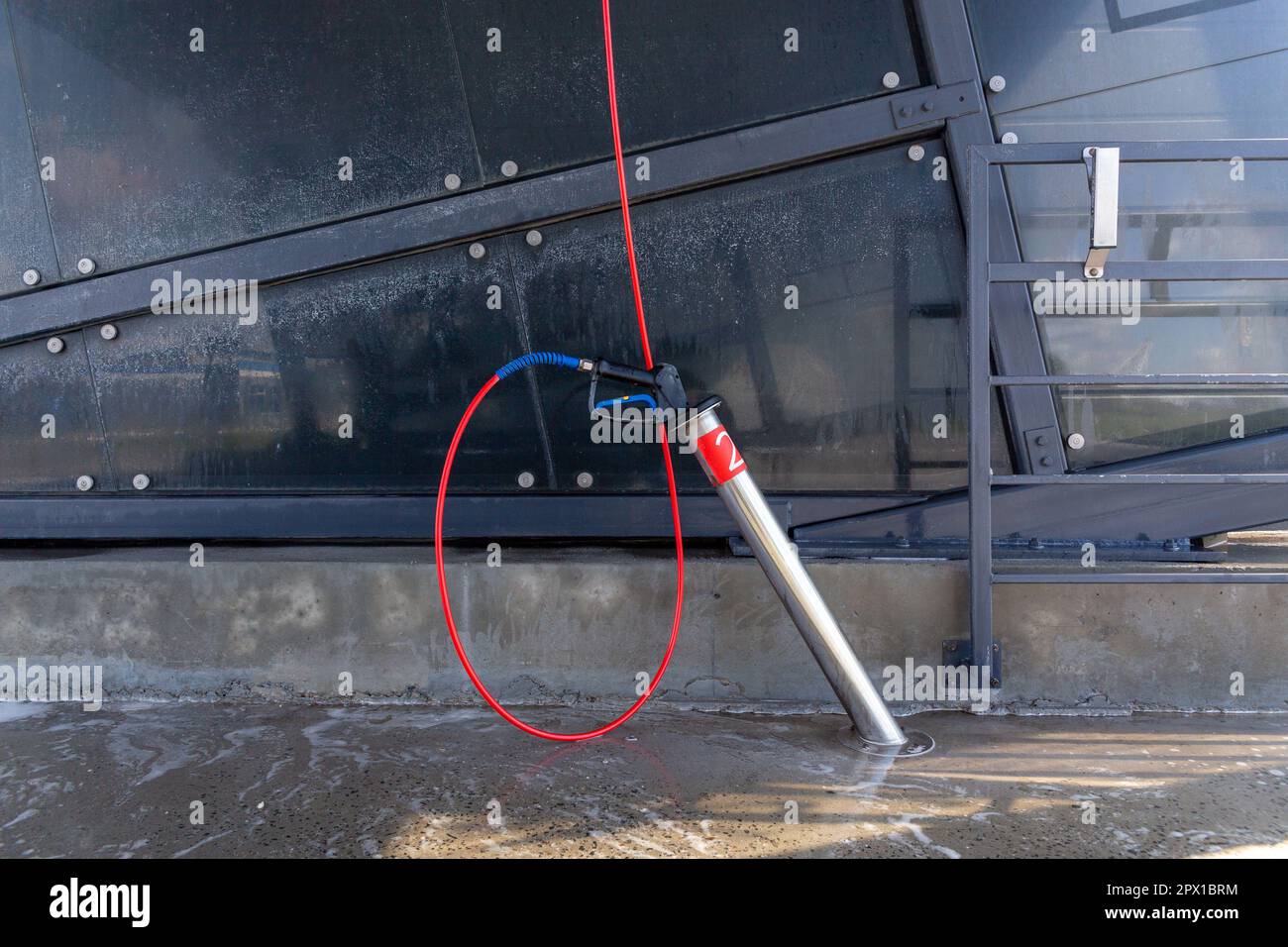 A high-pressure washing gun in a holder at a self-service car wash